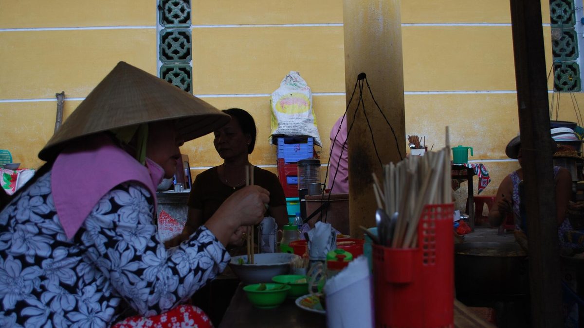 Một quầy cao lầu trong chợ Hội An với người bán đội nón lá