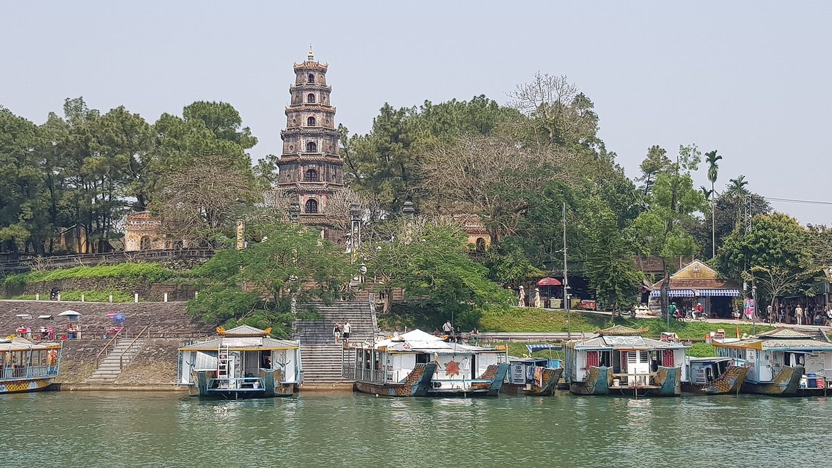 Chùa Thiên Mụ trên đồi Hà Khê nhìn từ sông Hương, phía trước là dãy thuyền rồng